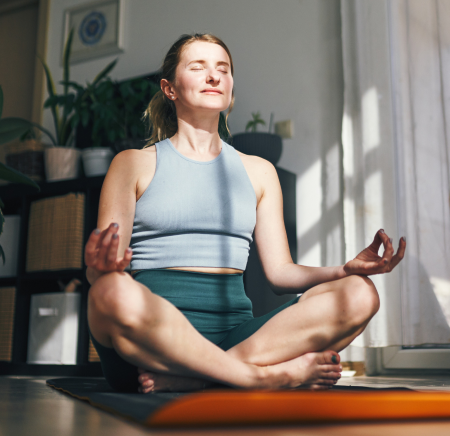 Person meditating on a yoga mat in living room