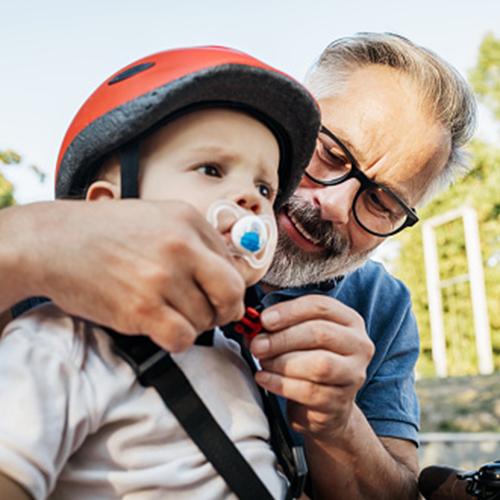 grandparent buckles strap on bike helmet for child with pacifier