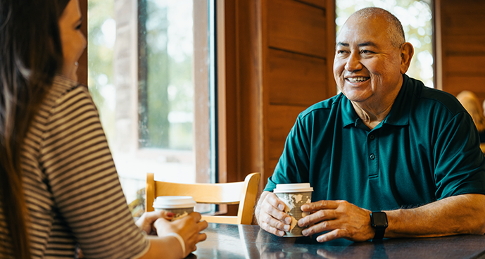 smiling middle-age man in conversation with friend at coffee shop