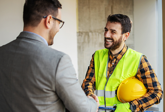 Two people shake hands at an indoor construction site