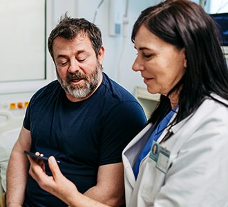Provider shows info on a smart phone to a patient in an exam room