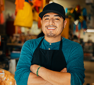 Young business owner smiles proudly while standing in their shop