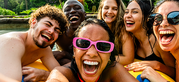 Six friends laugh together while on inflatables on sunny day