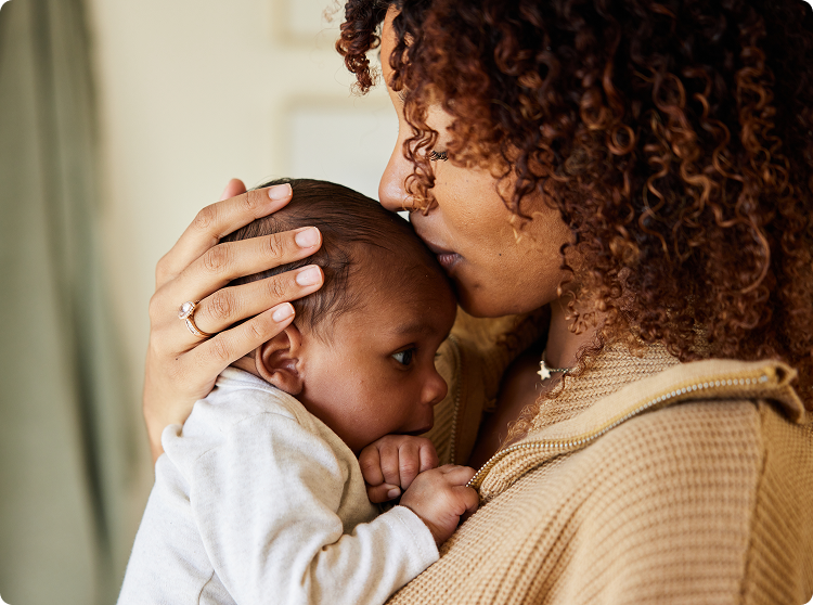 Mother cradles and kisses newborn baby