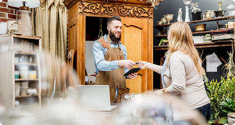 customer hands a smiling small business owner their credit card