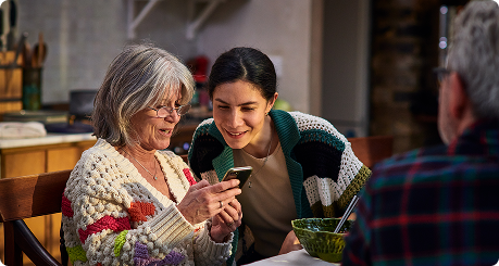 middle-aged mother and her daughter look together at smart phone