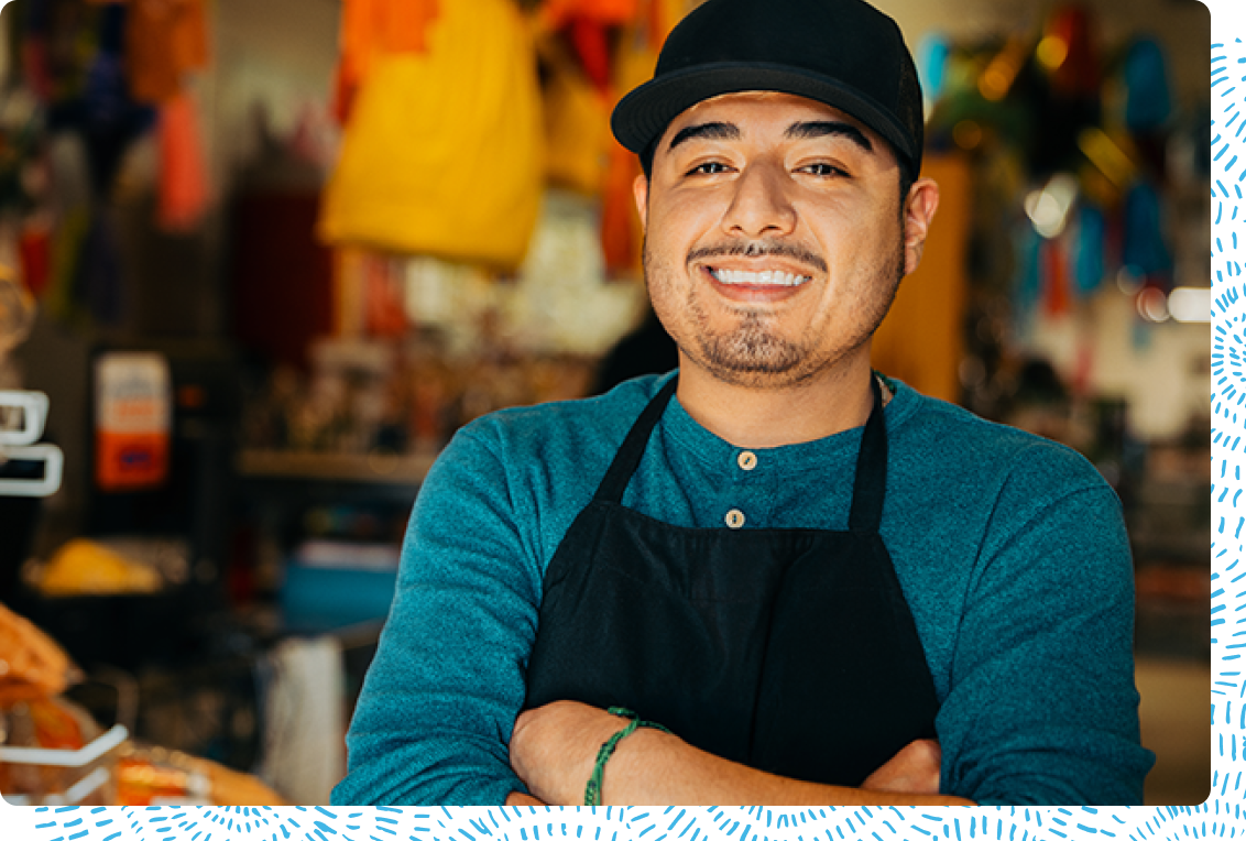 Young business owner smiles proudly while standing in their shop
