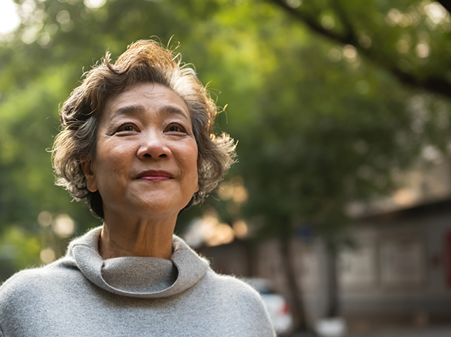 middle-aged person smiles walking on tree-lined street