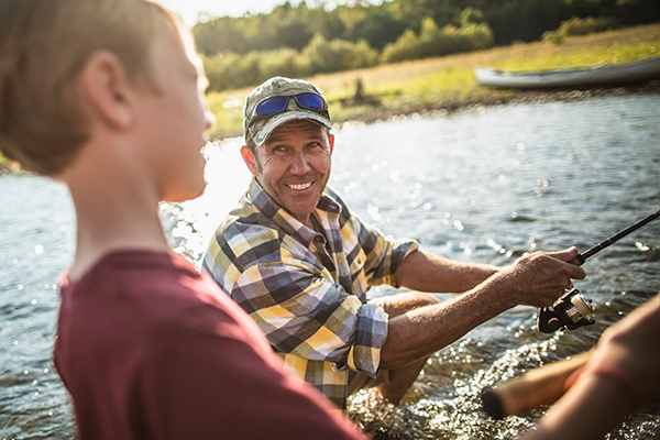 middle-aged grandparent fishes on lake with grandchild