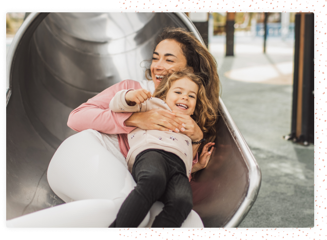 Mother and daughter going down slide