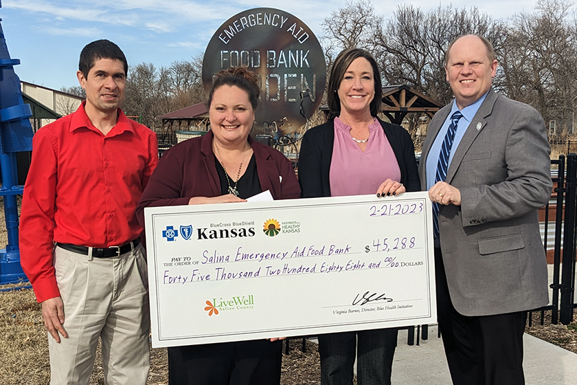 Four people pose together with big check for Salina Emergency Aid food bank