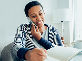 A woman on the phone writes in a notebook