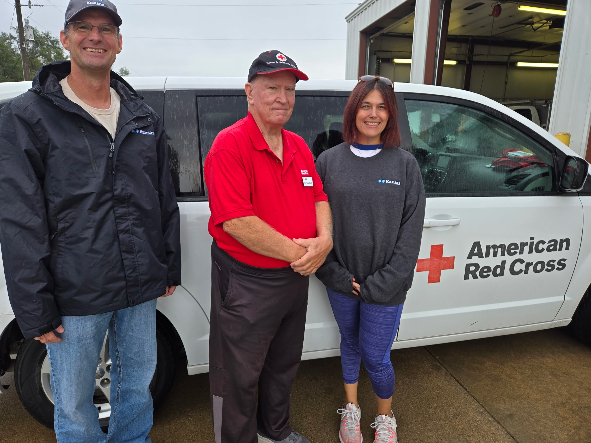 Two BCBSKS employees stand with an American Red Cross representative in front of a Red Cross van.