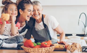 A grandmother, mother and daughter cooking and laughing in the kitchen