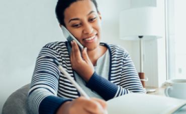 A woman on the phone writes in a notebook
