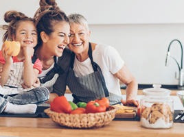 A grandmother, mother and daughter cooking and laughing in the kitchen