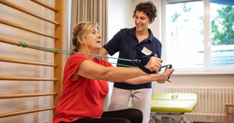 a nurse oversees a patient using exercise bands in a healthcare setting