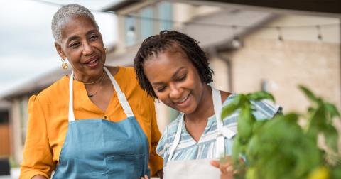 Two people in aprons working together near a garden planter.